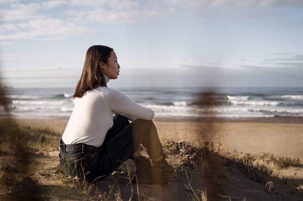 full shot woman sitting on a beach